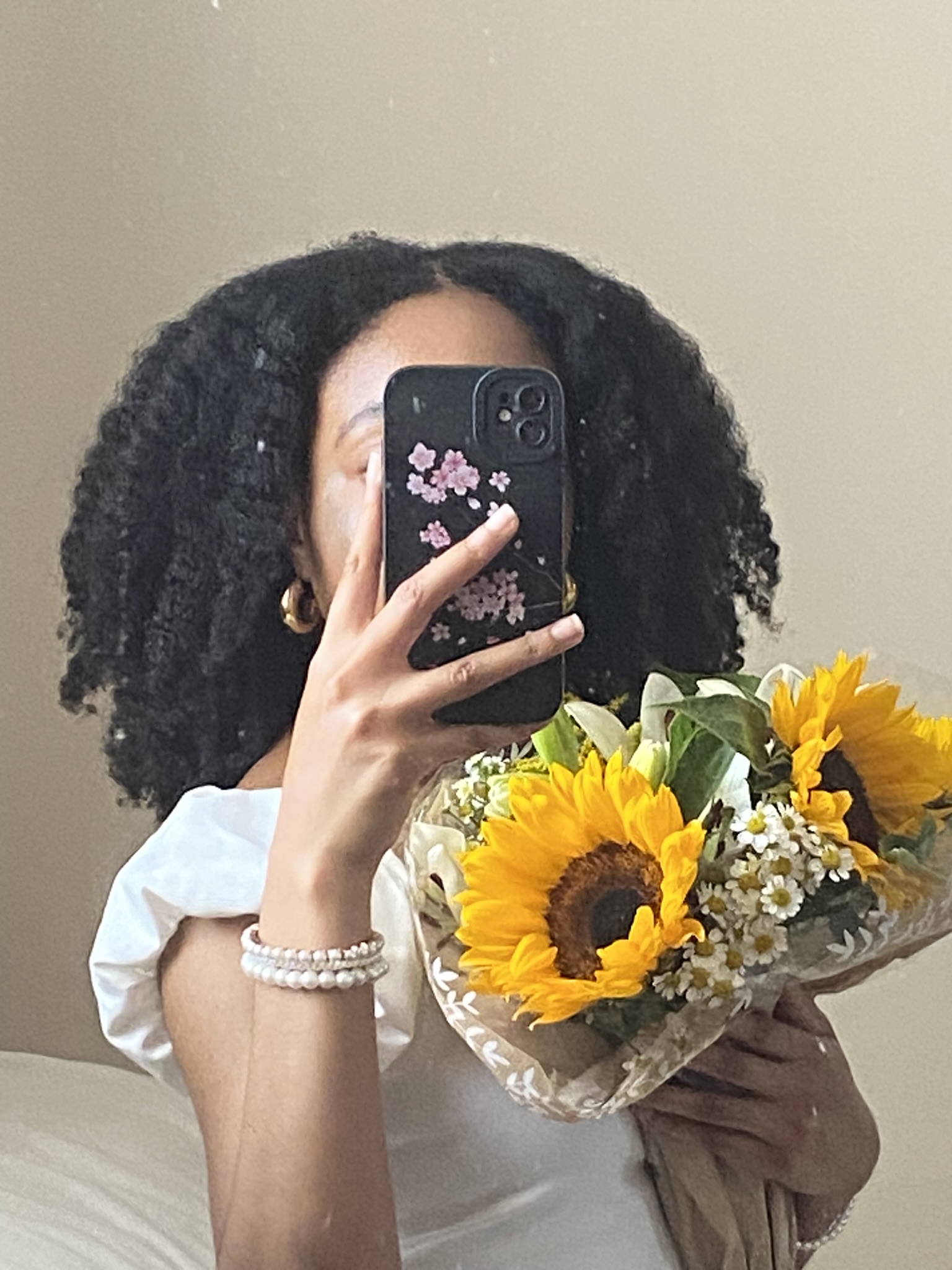 black girl with type 4 natural hair in a braid-out holding yellow flowers